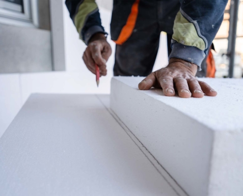 Worker use pen to mark the correct length and dimension of styrofoam during the wall insulation