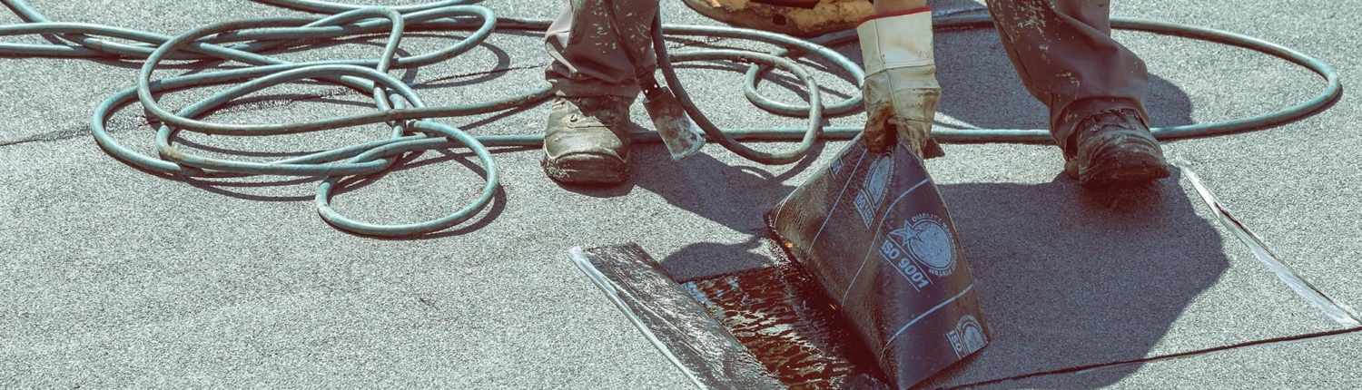 Worker installing modified bitumen roof material