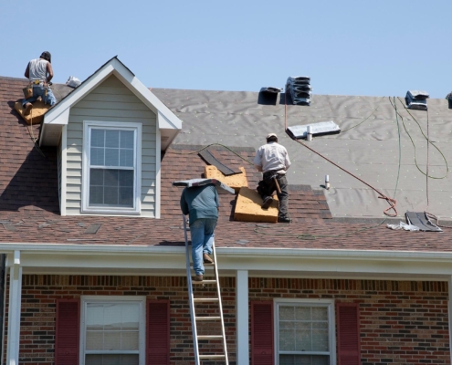 Workers putting new shingles on residential roof